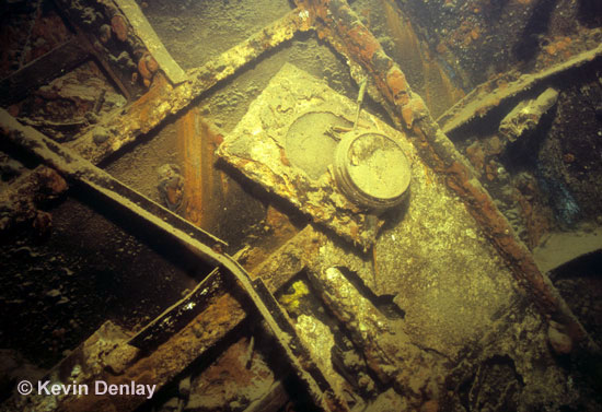A clock dangles from a bulkhead just inside the officer’s mess, or Longroom, on the wreck of Hr. Ms. De Ruyter. The wreck laid over to starboard on an angle of about 60 degrees