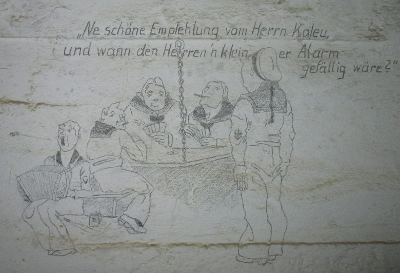 Γελοιογραφία σε τοίχο, φιλοτεχνημένη από γερμανό ναύτη, που έδρευε στο Ν.Ο.Φ. , κατά τη διάρκεια της Κατοχής. Επρόκειτο για προσωπικό της MAA-603 (Marine Artillerie Abteilung 603), δηλαδή της 603ης Ναυτικής Πυροβολαρχίας. Είναι αξιοσημείωτο ότι αυτό το μικρό «έργο τέχνης» επιβίωσε για σχεδόν 75 χρόνια, μέσα σε ένα σκοτεινό καταφύγιο.