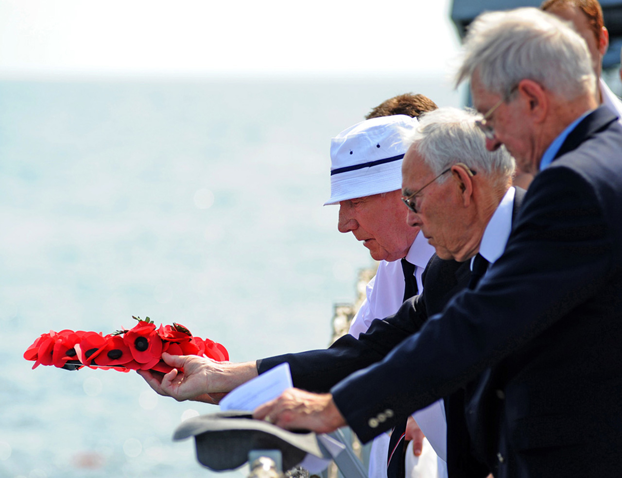 Full of thoughtfulness and respect, the HMS Exeter sinking veterans solemnly prepare to place a floral wreath over the wreck of their old ship.