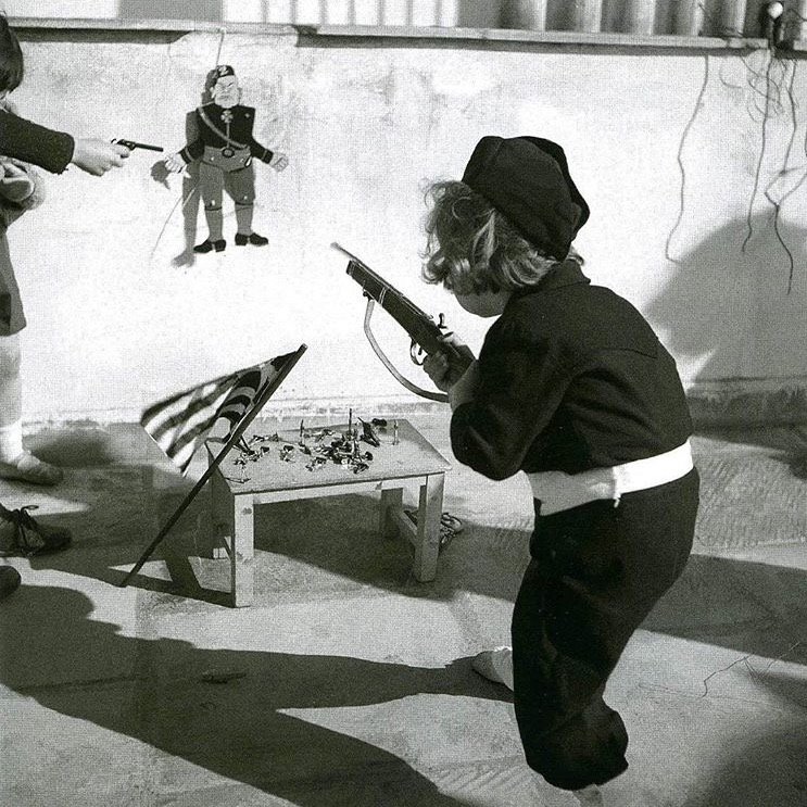 A child wearing the EON uniform (National Youth Organisation) points the weapon to a figure of Mussolini. Athens, 1940